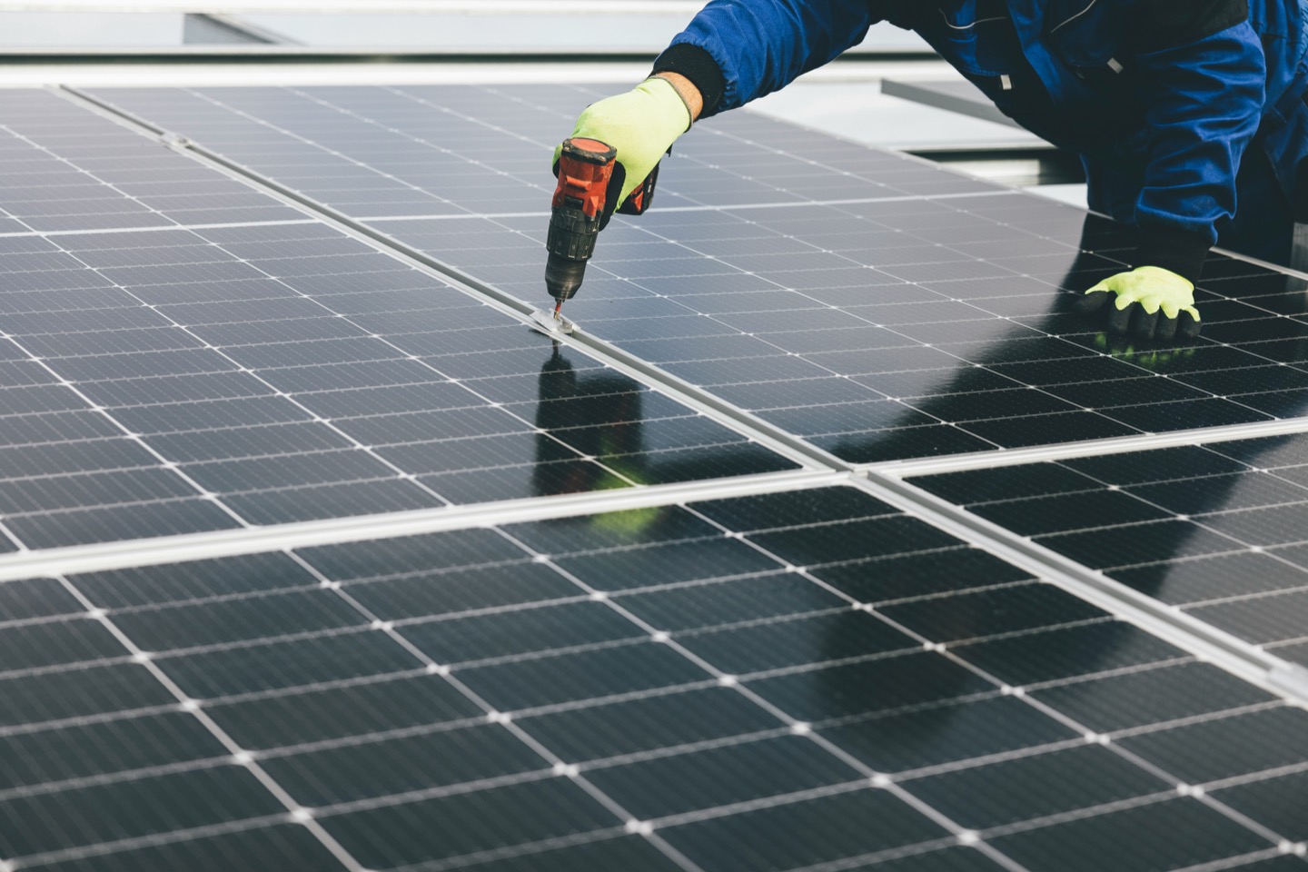 Solar installer securing rooftop solar panels with a drill